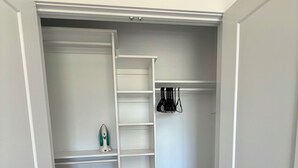 Un vestidor amplio con interior blanco, suelo de madera y una percha con bolsos.
