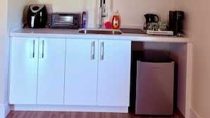 Eine kompakte Küche mit Einbaugeschirrspüler, Toaster, Wasserkocher und Kaffeemaschine.