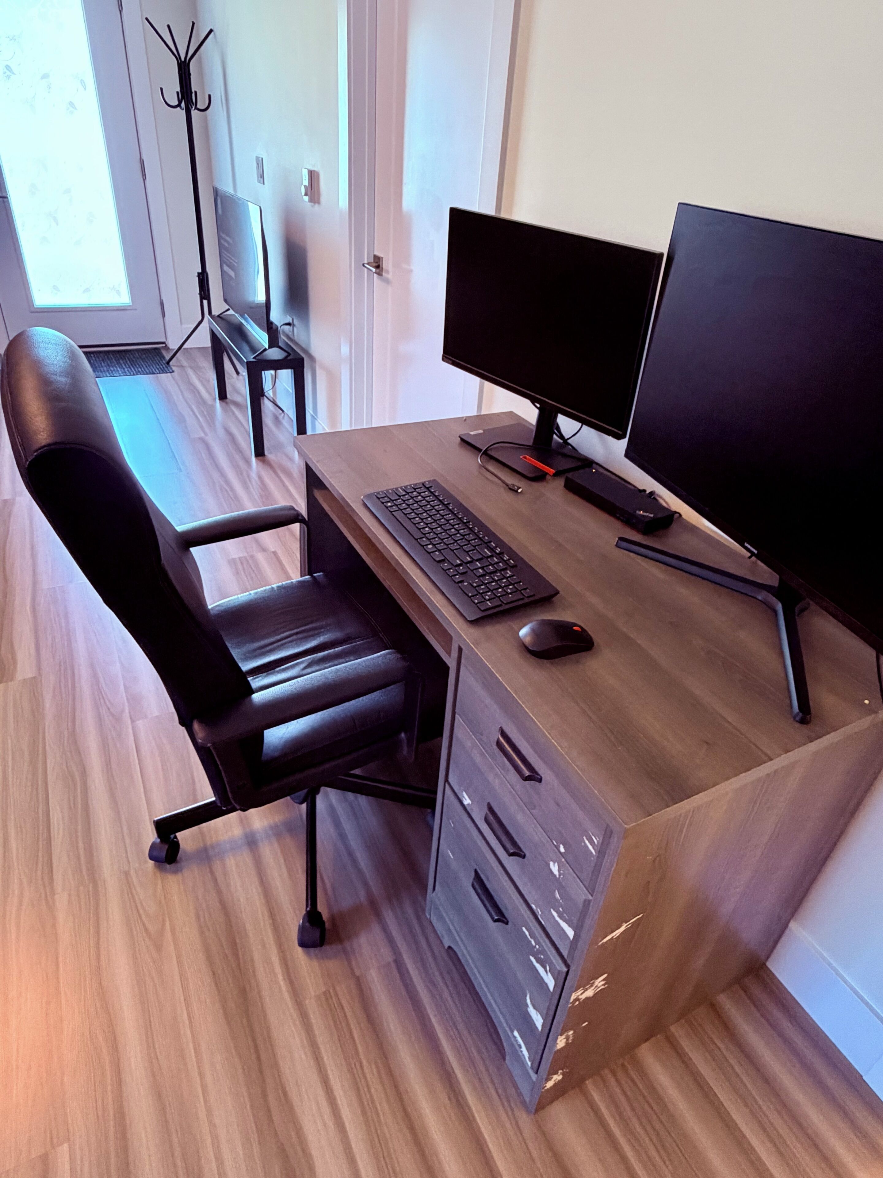 A modern office desk with a computer, keyboard, mouse, and a chair.