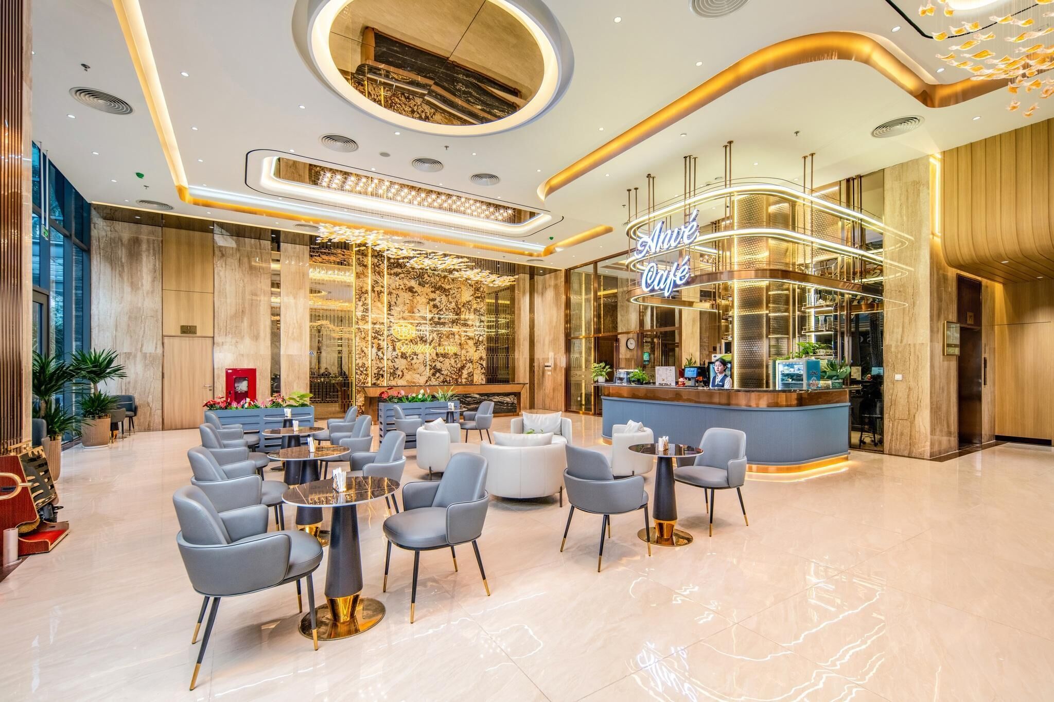 Un moderno vestíbulo de hotel con recepción, zona de estar y cafetería.