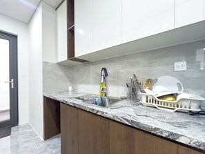Eine moderne Küche mit Marmorarbeitsplatte, Edelstahlspüle und Holzschränken.