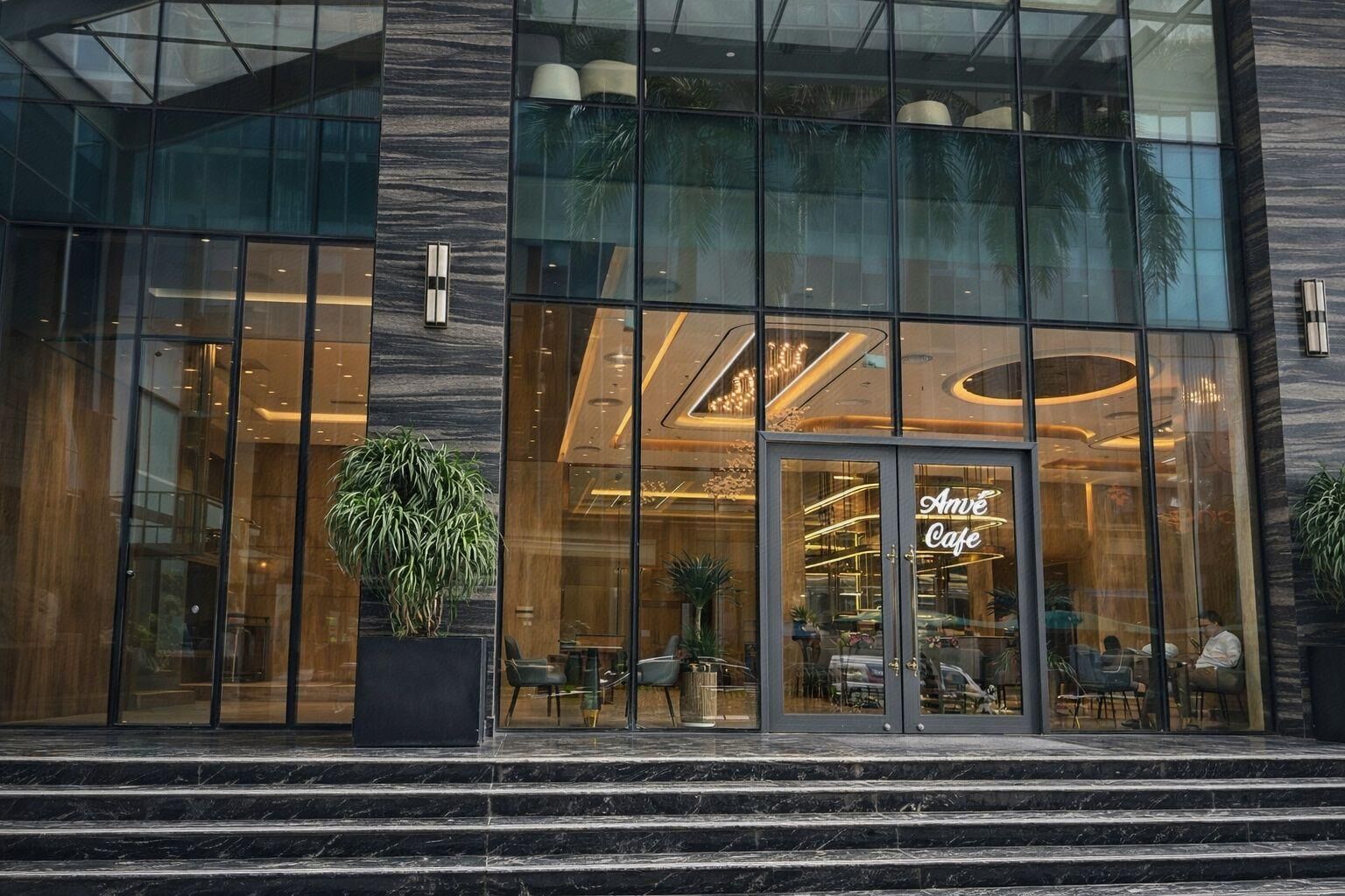 Een modern gebouw met grote glasramen, een opvallend 'Amé Café' bord en een trap naar de ingang.