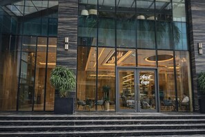A modern building with large glass windows, a prominent 'Amé Café' sign, and a staircase leading to the entrance. - The Elite Premier Suites (Hanoi)