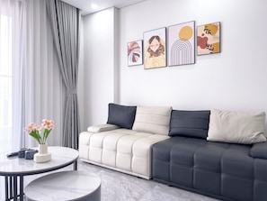 A modern living room with a sofa, a round table, and artwork on the wall. - The Elite Premier Suites (Hanoi)