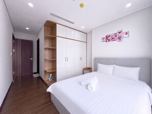 A hotel room with a large bed, a wardrobe, and a small bedside table. - The Elite Premier Suites (Hanoi)