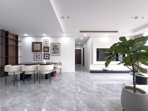 A modern interior with a dining area, wall-mounted artwork, and a potted plant. - The Elite Premier Suites (Hanoi)