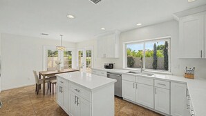 A modern kitchen with white cabinetry, a large island, and a view of greenery outside. - Resort backyard and pool - close to everything (Mesa)