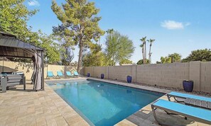 Ein Pool mit Liegestühlen und einer überdachten Sitzgelegenheit.