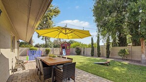 A patio with a table and chairs, a yellow umbrella, and a children's play structure. - Resort backyard and pool - close to everything (Mesa)