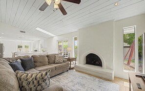 Ein modernes Wohnzimmer mit Kamin, einer Couch und einem Essbereich im Hintergrund.