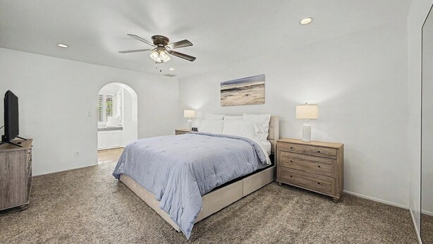 A bedroom with a bed, a nightstand, a ceiling fan, and a painting on the wall. - Resort backyard and pool - close to everything (Mesa)
