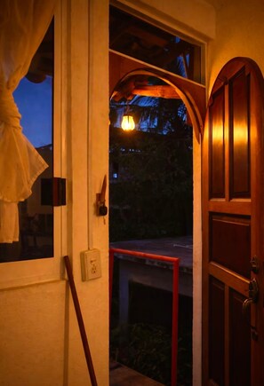 A wooden door with a glass panel, a red railing, and a hanging light fixture.