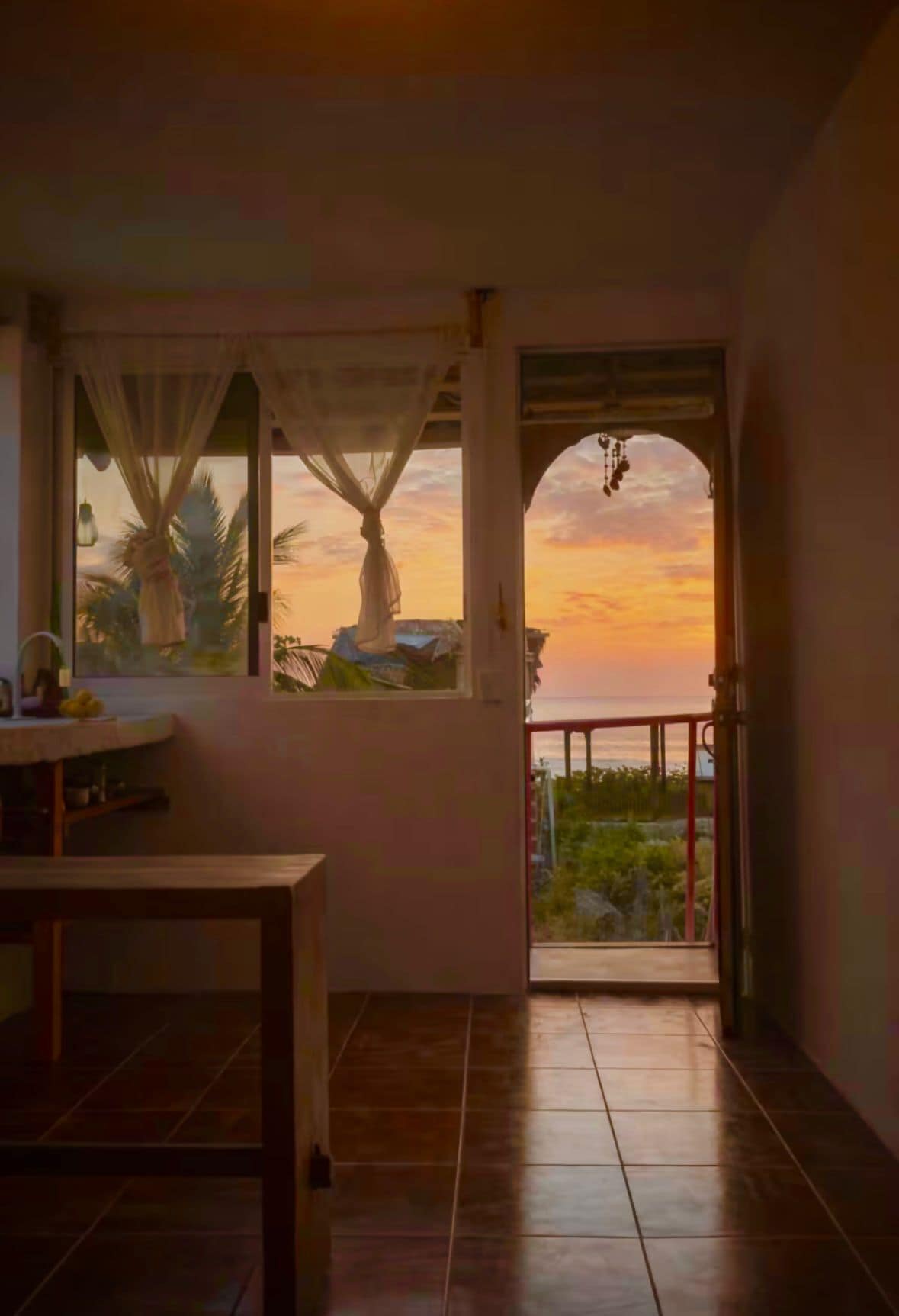 Een kamer met uitzicht op een zonsondergang, een tafel en een deur naar buiten.