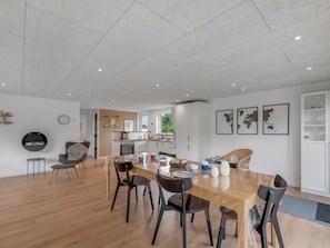 A spacious dining area with a long wooden table, modern chairs, and a kitchen in the background. - "Jonnhild" - 100m to the fjord by Interhome (Tarm)