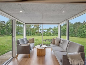 A modern living room with a glass ceiling, a grey sofa, a round wooden coffee table, and a view of a green garden. - "Jonnhild" - 100m to the fjord by Interhome (Tarm)