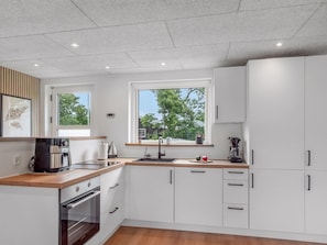 A modern kitchen with white cabinets, a wooden countertop, and a window with a view of trees. - "Jonnhild" - 100m to the fjord by Interhome (Tarm)