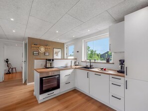 A modern kitchen with a built-in oven, a coffee maker, and a window providing a view of the outdoors. - "Jonnhild" - 100m to the fjord by Interhome (Tarm)
