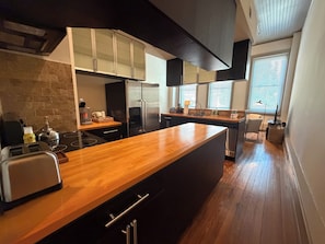 A modern kitchen with a wooden countertop, stainless steel appliances, and a brick accent wall. - Right in the heart of downtown Macon (Macon)