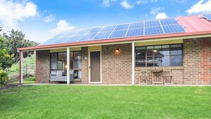 A building with a brick exterior, a covered porch, and solar panels on the roof. - NR 4 Cove Apartment Carrickalinga (Carrickalinga)