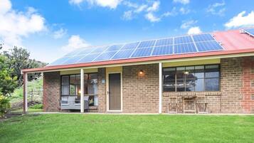 A building with a brick exterior, a covered porch, and solar panels on the roof.