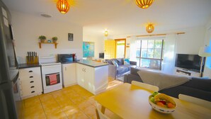 A compact living space with a kitchenette, dining area, and seating area. - NR 4 Cove Apartment Carrickalinga (Carrickalinga)