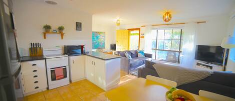 Un espace de vie compact comprenant une kitchenette, un coin repas et un coin salon.