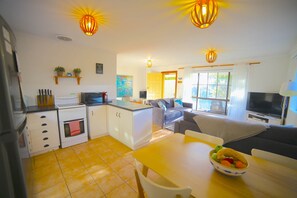 A compact living space with a kitchenette, dining area, and seating area. - NR 4 Cove Apartment Carrickalinga (Carrickalinga)
