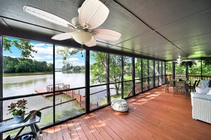 Une terrasse couverte avec vue sur un lac, dotée d’un ventilateur de plafond et de mobilier d’extérieur.