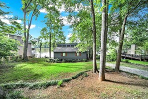 A residential property with a well-maintained lawn, a house with a dark exterior, and a dock extending into a body of water.