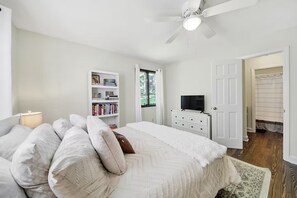 A bedroom with a bed, a bookshelf, a television, and a door leading to another room.