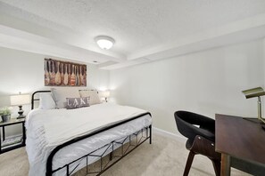 A bedroom with a bed, bedside tables, a desk, and a chair.
