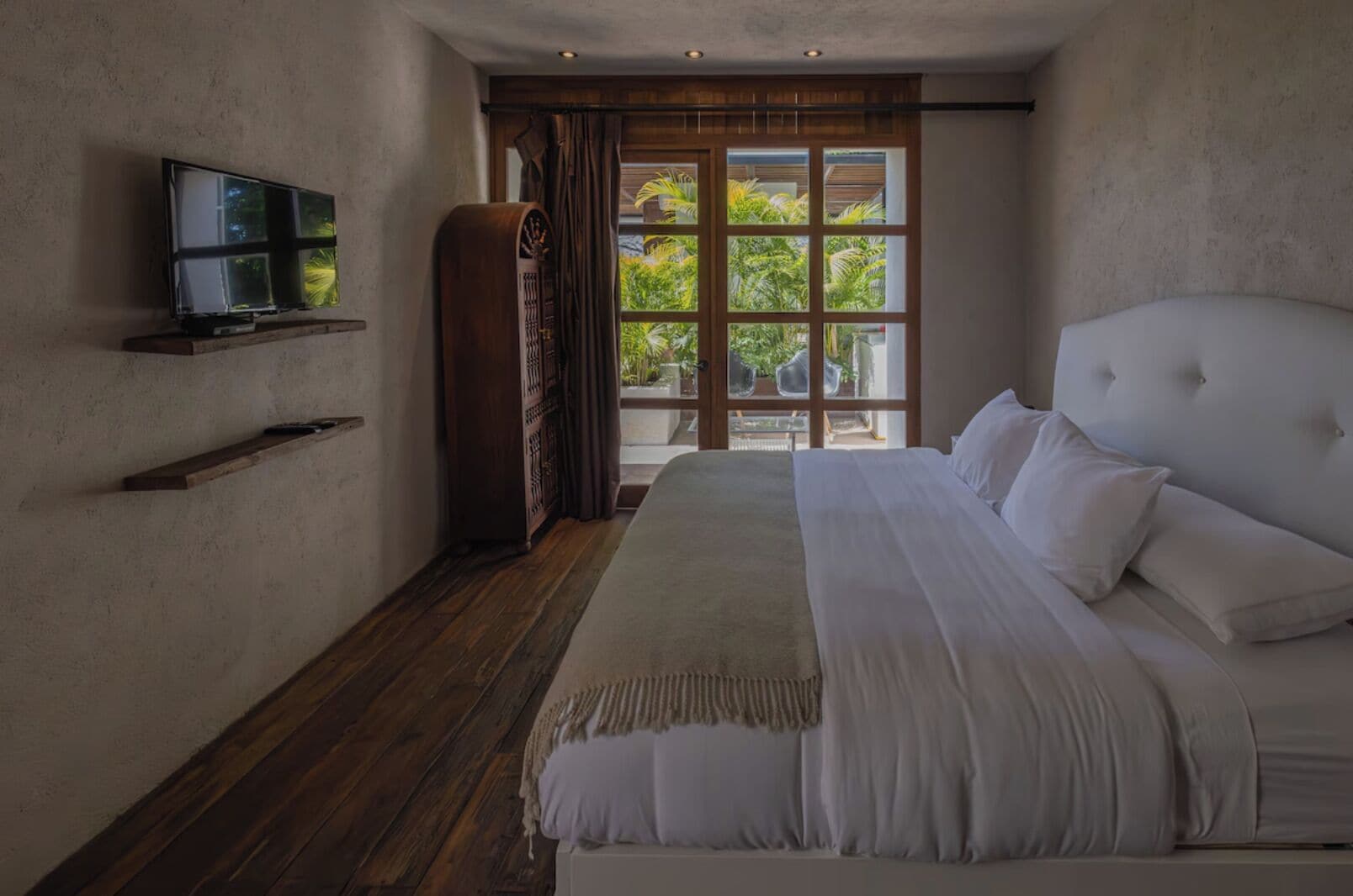 Un dormitorio con una cama grande, un televisor en la pared y vistas al exterior.