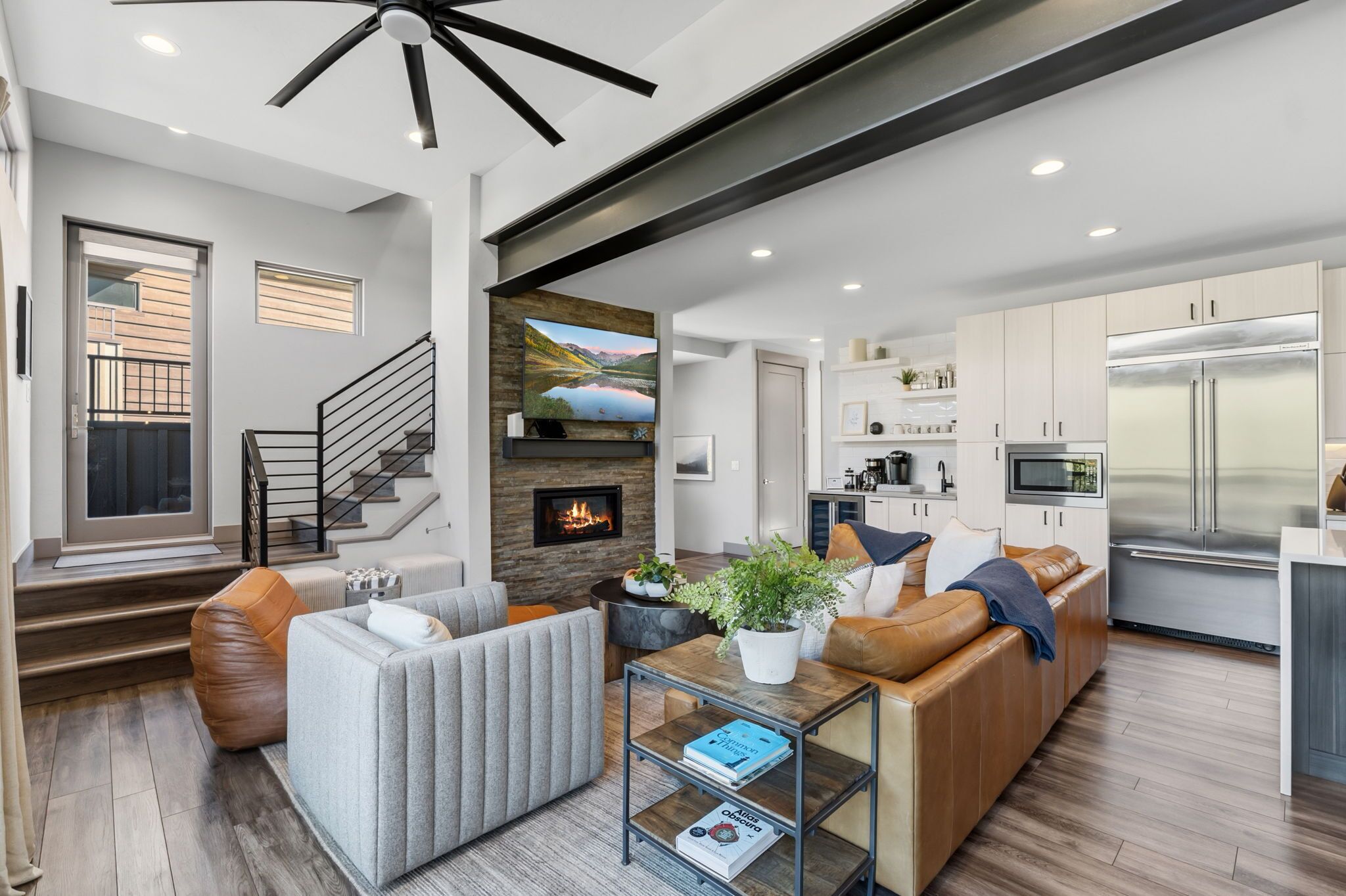 A modern living room with a fireplace, a sofa, a coffee table, and a kitchen area with a refrigerator and microwave.