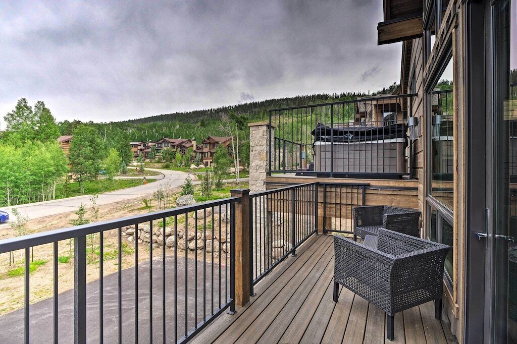 A wooden deck with outdoor furniture, a grill, and a view of a mountainous area.