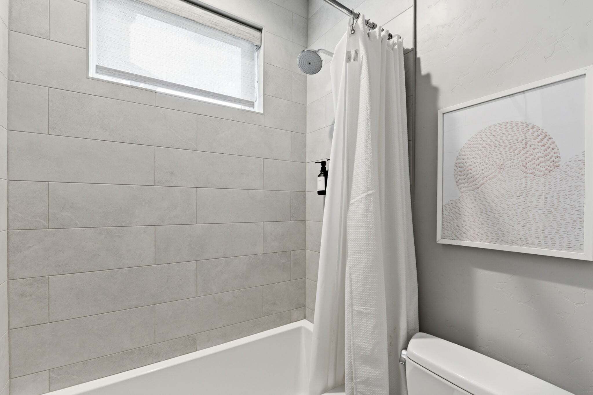 Een badkamer met een douche, een raam en een handdoekhouder.
