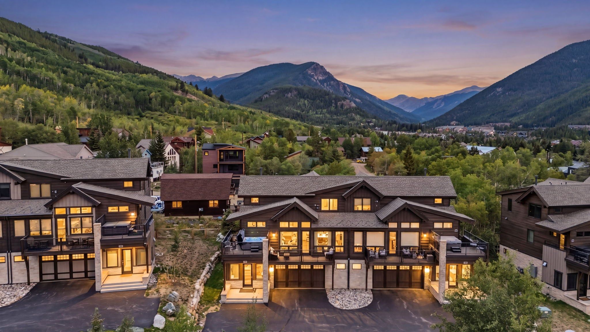 A modern resort with multiple buildings, a well-maintained lawn, and a mountainous backdrop.