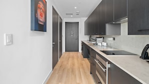 A modern kitchen with a wooden floor, dark cabinets, and a large window. - Experience Luxury At The E11EVEN Residences (Miami)