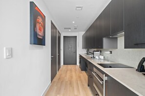 A modern kitchen with a wooden floor, dark cabinets, and a large window. - Experience Luxury At The E11EVEN Residences (Miami)
