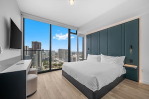 A modern bedroom with a large bed, a desk, and a view of a cityscape through large windows. - Luxury E11EVEN Skyline Views & ELITE Amenities (Miami)