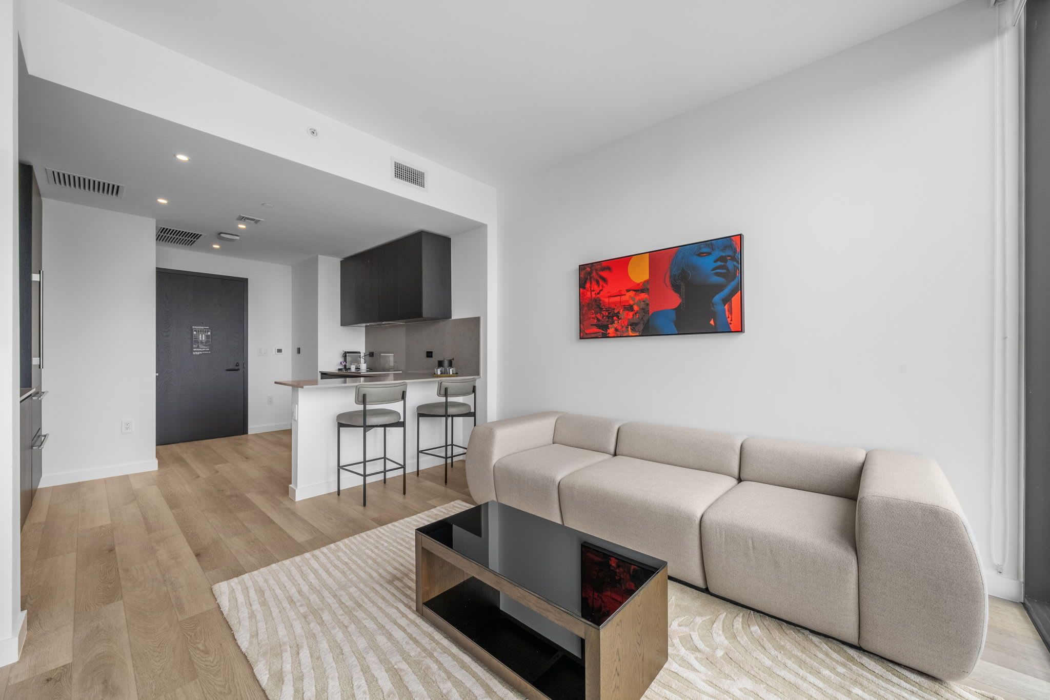 Ein modernes Wohnzimmer mit einer Couch, einem Couchtisch und einer Küchenzeile im Hintergrund.