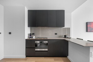 A modern kitchen with dark cabinetry, a built-in oven, and a countertop. - Luxury E11EVEN Skyline Views & ELITE Amenities (Miami)