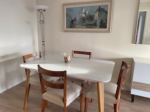 A dining area with a white table, four wooden chairs, a vase with dried flowers, and a painting on the wall. - Torre de las Américas Apartment, Punta del Este (Punta del Este)