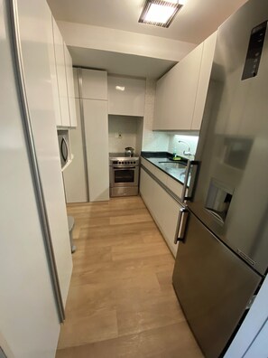 A modern kitchen with stainless steel appliances, white cabinetry, and a wooden floor. - Torre de las Américas Apartment, Punta del Este (Punta del Este)