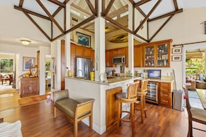 Una cocina amplia con armarios de madera, una isla central con taburetes y vista al área de comedor.