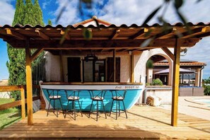A wooden deck with a bar area featuring a blue boat-shaped bar counter and three stools. - Villa Sleeps 12 with Outdoor Pool (Laroque-Des-Albères)