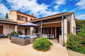 A two-story house with a covered patio, outdoor furniture, and a garden area. - Villa Sleeps 12 with Outdoor Pool (Laroque-Des-Albères)