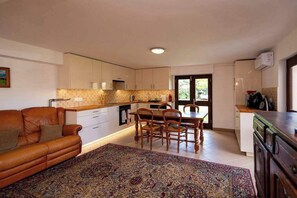A modern kitchen with a dining area, a sofa, and a patterned rug. - Villa Sleeps 12 with Outdoor Pool (Laroque-Des-Albères)