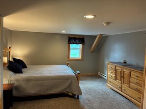 Ein Schlafzimmer mit Bett, Nachttisch, Schminktisch, einem Fenster mit Blick und Deckenventilator.