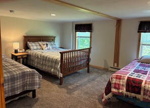 A bedroom with a wooden bed, two bedside tables, a nightstand, a window with curtains, and a carpeted floor. - Rustic, serene 2-bedroom house in Constableville. (Constableville)