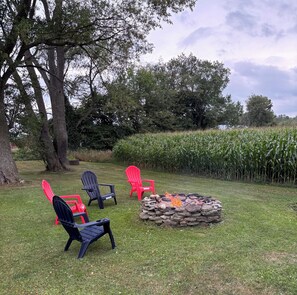 A grassy outdoor area with a stone fire pit and Adirondack chairs. - Rustic, serene 2-bedroom house in Constableville. (Constableville)